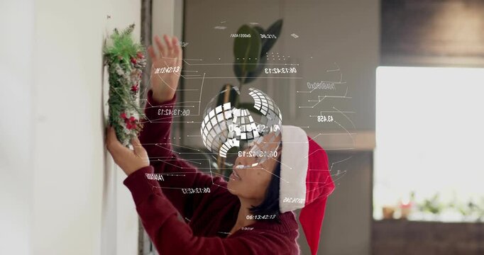 Reaching for wall hook, woman lifting wreath while holo data visuals guiding holiday decor