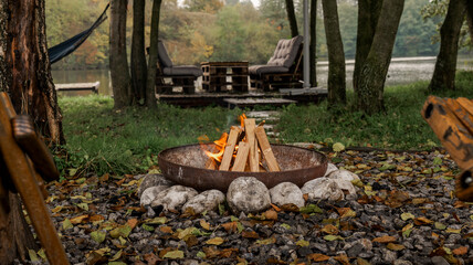 Cozy outdoor scene with a fire pit, seating, and a hammock near a lake