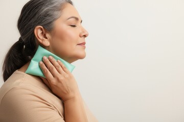 Mature woman applying a cold pack to her neck for pain relief. Menopause and hot flash symptom concept. Health and wellness with copy space