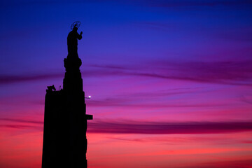 The silhouette of a religious statue stands against a winter sunset, where deep blues and soft pinks blend into violet. Sameiro Sanctuary, Braga, Portugal. © bruno ismael alves