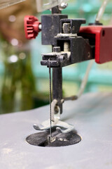 Detailed shot of a scroll saw's cutting head with a fine blade and collected dust, portraying precision woodworking tool, emphasizing craftsmanship and machinery in workshop setting.