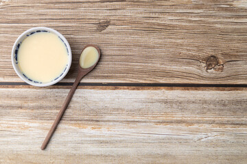 Condensed milk in a bowl over wooden table with copy space