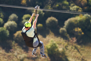 Ziplining. A woman descends a metal cable over a gorge. Close-up. © ROMAN DZIUBALO