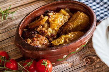Traditional cabbage rolls (sarma) served in a rustic brown bowl, showcasing tender leaves stuffed with a savory meat and rice filling. The warm, hearty dish is highlighted by natural lighting, emphasi