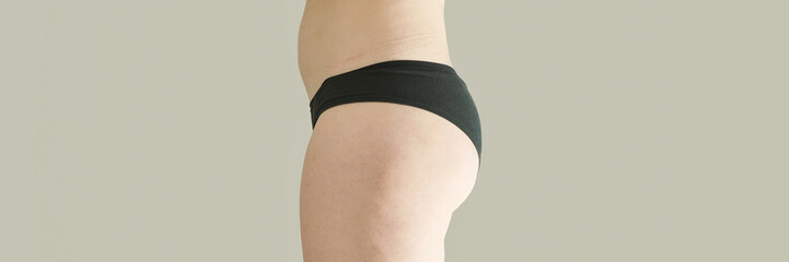Caucasian adult female in black underwear side view on neutral background showing body silhouette.
