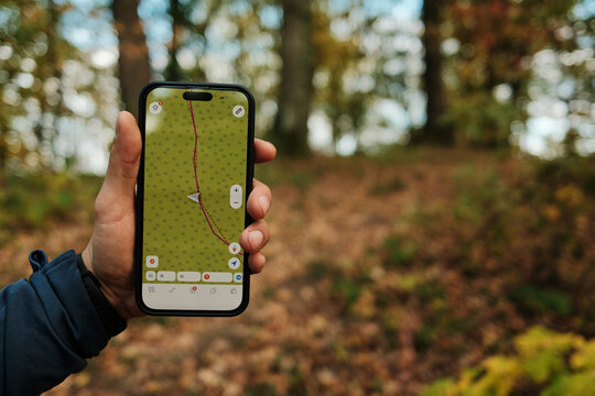 Close-up of man holding smartphone with GPS navigation app while hiking in autumn forest of Fruska Gora National Park Serbia. Travel concept