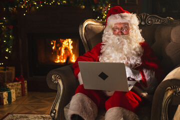 Merry Christmas. Santa Claus with laptop reading letters from children typing buying presents gifts...