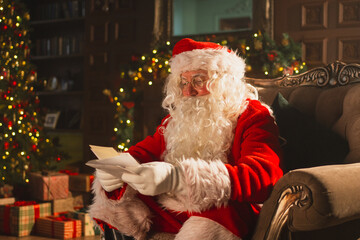 Merry Christmas. Happy Santa Claus reading letters from children in festive Christmas living room....