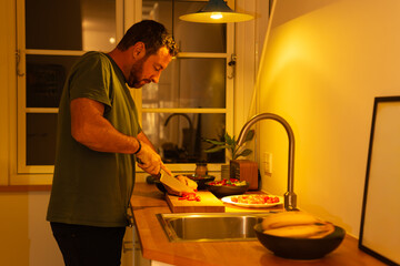 Man cooking dinner in a Danish style kitchen illuminated with cozy warm light.