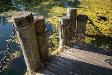 Naklejka premium Logs with metal chains, viewing deck of pond.