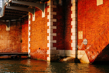 Historic red brick bridge over water with architectural details at sunset
