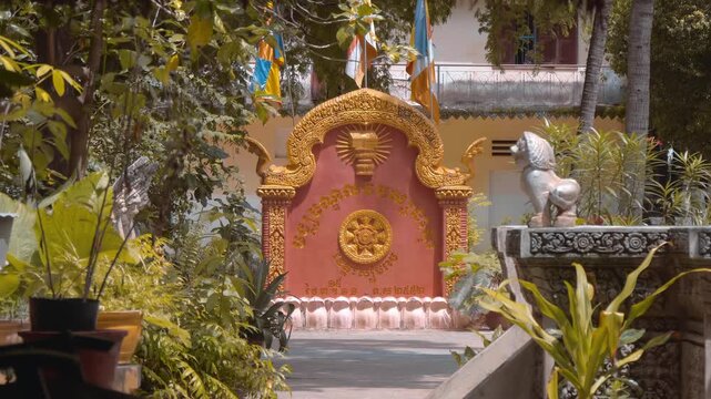 Golden Dharmachakra and Buddhist flags are placed on the entrance tablet of a Khmer temple. Siem Reap, Cambodia. Shot in motion