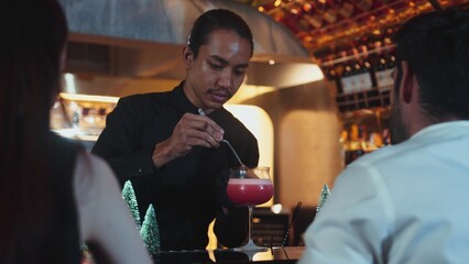 Focused on mixed punch cocktail Christmas theme garnishing with burning cinnamon and star anise by bartender, serving decorated green neon snow Christmas tree bar special cool drink luxury. Vinosity.