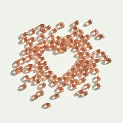 Heart shape formed by spread vitamins pills on white background for health and wellness concept.