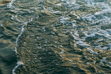 Ocean waves crashing with foam and sunlight reflections at beach