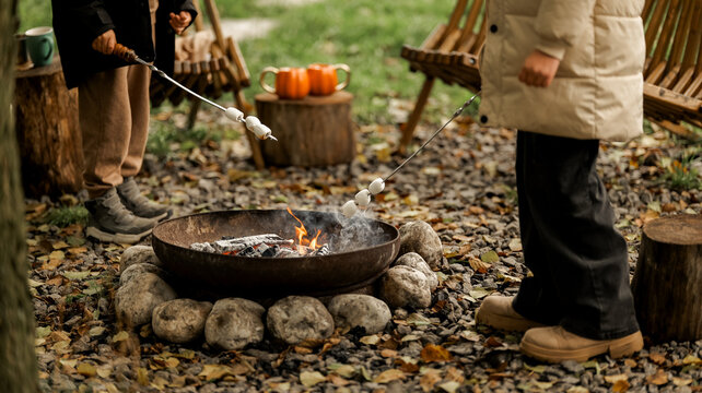 People roasting marshmallows over a campfire on a cool autumn day - Powered by Adobe