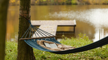 Relaxing hammock with a book by the lake on a peaceful autumn day