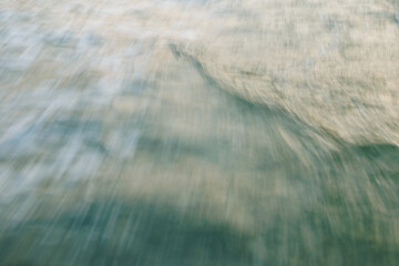 Blurred abstract ocean wave texture with green and beige tones