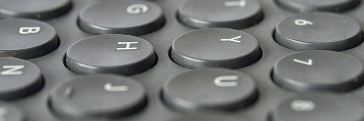 Close-up image of round black keyboard keys with highlighted letters and symbols.