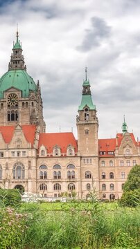 Hyperlapse of Hanover's New Town Hall, a landmark castle-like structure surrounded by park and lake under a cloudy sky. Reflections on water and greenery frame this iconic cityscape timelapse. Germany
