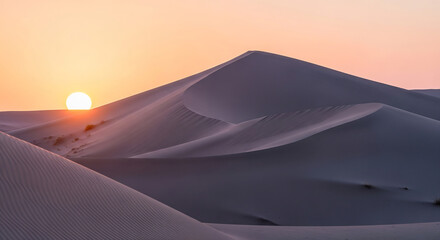 Expansive desert sand dunes under a warm glowing sky.