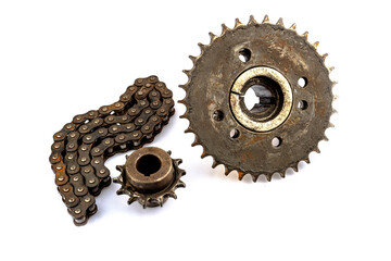 An old motorcycle sprocket and chain, thickly coated in black oil and grease, on a white background. Perfect for motorcycle repair and maintenance topics.