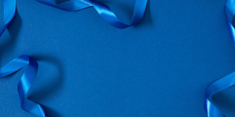 Blue satin ribbon on blue background. Minimal festive layout with copy space. Elegant background...