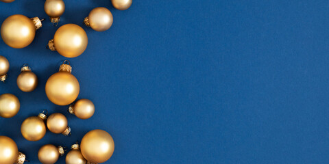 Golden Christmas baubles on blue background. Minimal festive composition with copy space. Elegant winter layout for greeting cards, banners, and holiday designs.