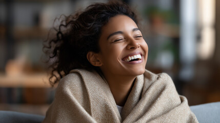 Young woman laughing while relaxing at home side back angle on couch cozy throw authentic happiness faceless no visible faces lifestyle with copy space