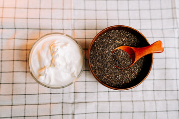 Roasted chia seeds in a bowl beside a creamy yogurt on a checkered cloth
