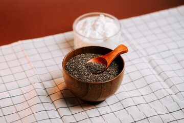 Roasted chia seeds served in a wooden bowl with yogurt on a checkered cloth