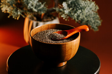 Roasted chia seeds served in a wooden bowl with a spoon on a dark table