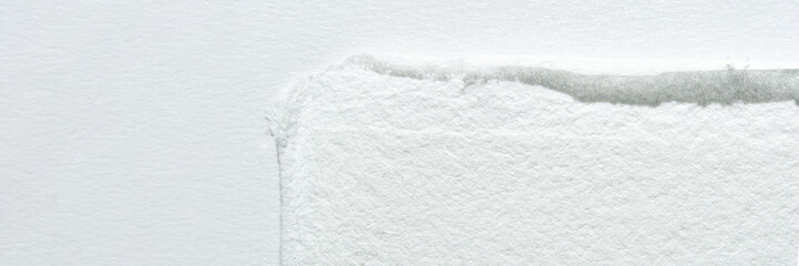 Close-up of textured white toilet paper edge against smooth white background.