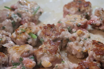 Uncased sausage meat mixed with herbs and spices, seared and sizzling in frying pan.