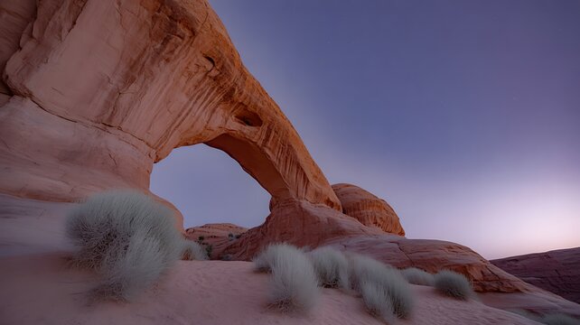 Natural sandstone arch formation in desert landscape at twilight with subtle stars visible in the sky - Powered by Adobe
