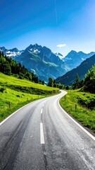 Fototapeta premium Winding road through lush green valley, leading to majestic snow-capped mountains