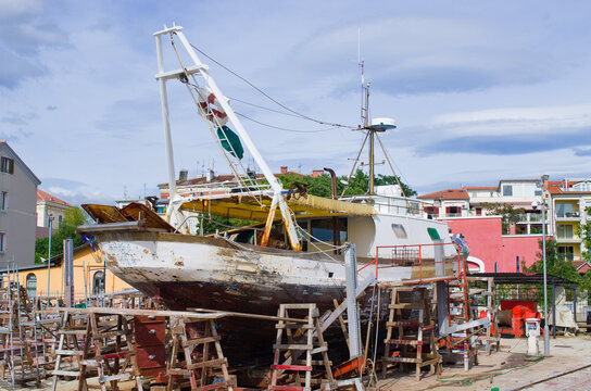Dilapidated fishing boat undergoing repairs ashore