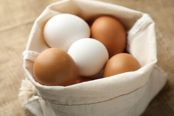 Raw chicken eggs in sack on table, closeup