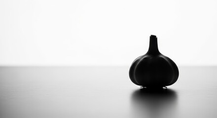 Fototapeta premium Minimalist black and white silhouette of a single garlic bulb on a smooth surface