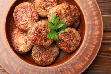 Delicious meat patties with parsley on wooden table, top view