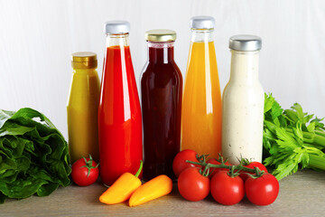 Bottles of different tasty sauces and products on grey wooden table, closeup