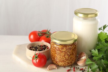 Bottles of different tasty sauces and products on white wooden table, closeup. Space for text