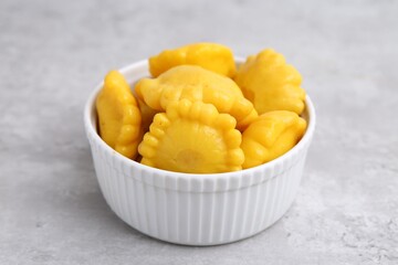 Pickled pattypan squashes in bowl on light grey table, closeup