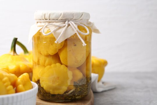 Pickled pattypan squashes on light grey table, closeup. Space for text