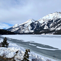 Snow covered mountains and frozen lake under cloudy sky landscape scene