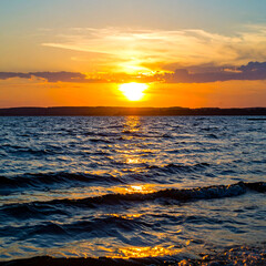 Sunset over calm water with golden sunlight and cloudscape scenery