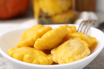 Pickled pattypan squashes in bowl on grey table, closeup
