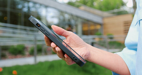 Close-up side view of a woman s hand interacting with a smartphone outdoors, tapping and scrolling on the screen, representing digital communication and modern mobile technology in everyday life