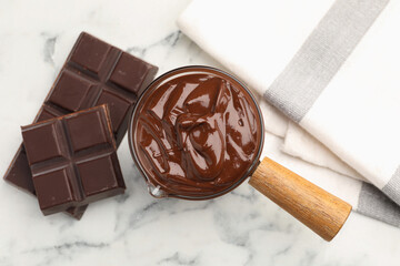 Melted chocolate and pieces on white marble table, flat lay