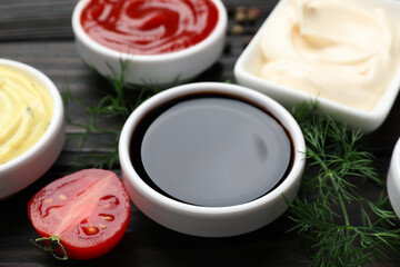 Different sauces and herbs on wooden table, closeup